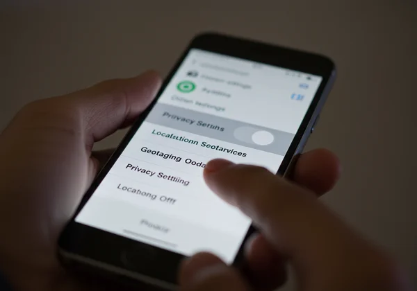 Hand disabling location services on a smartphone.